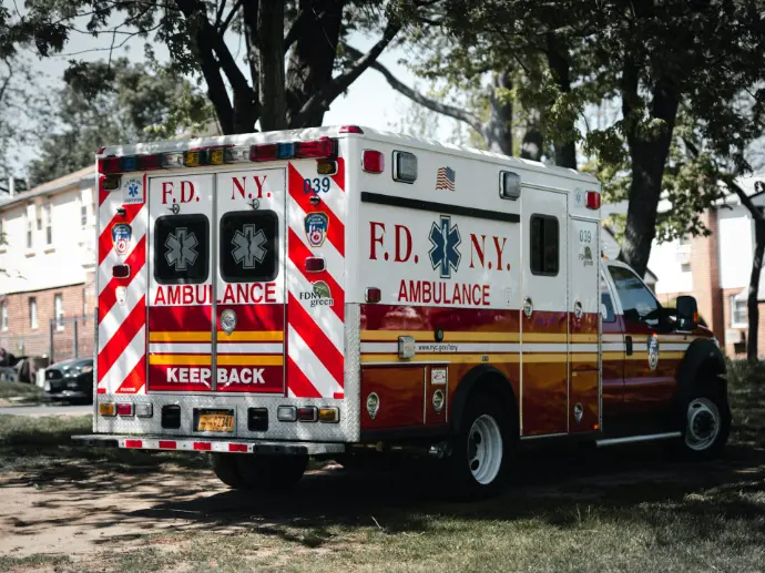 red and white ambulance truck parked near green trees during daytime